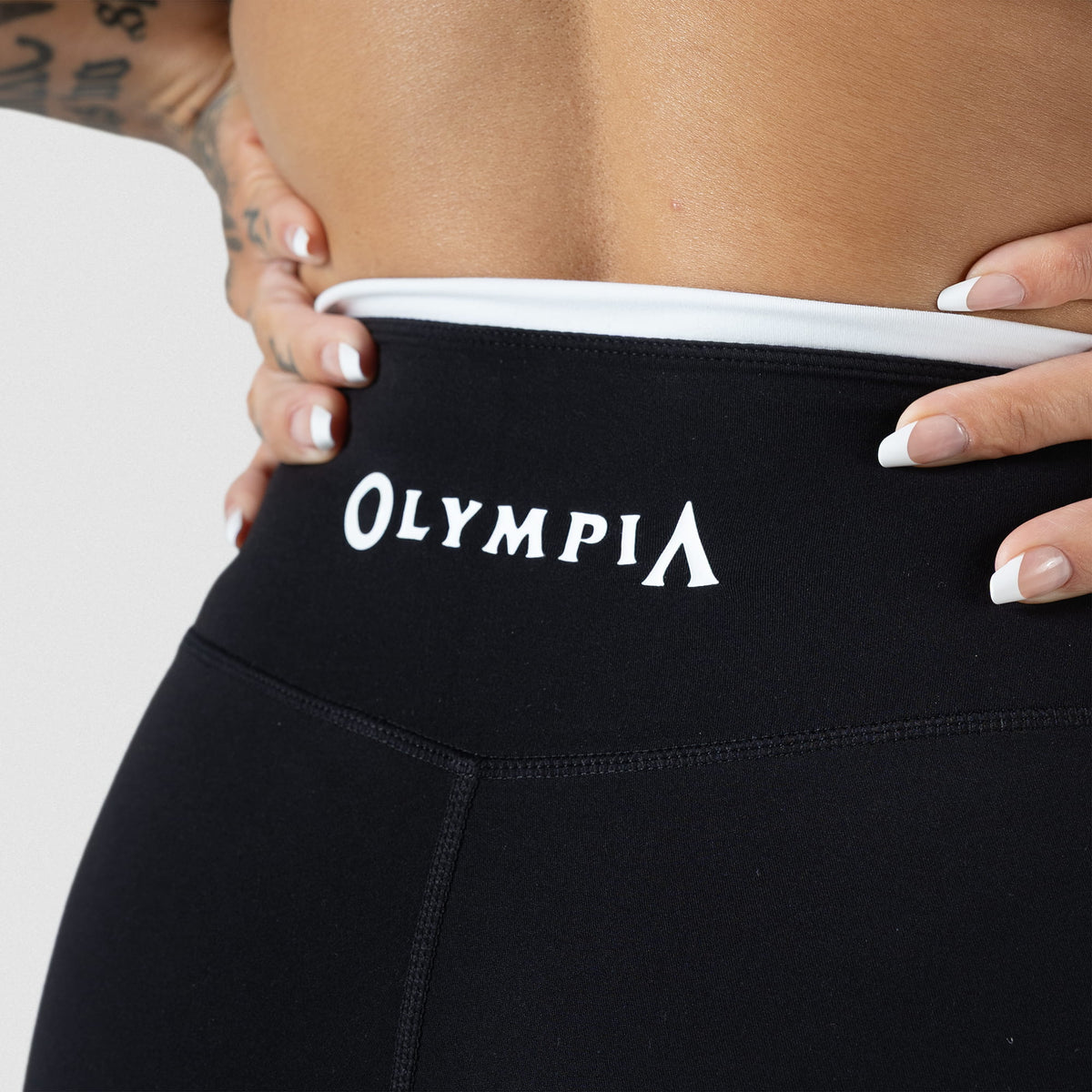Close up view of "Olympia" wordmark logo above the glute seam of the Olympia 4" shorts
