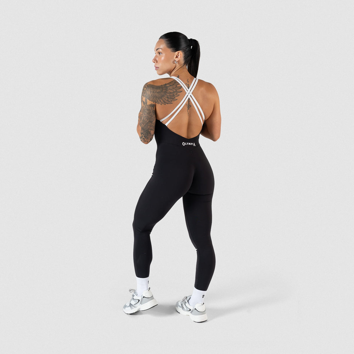 Full back view of Model wearing the Olympia Bodysuit featuring black and white contrasting details and white Olympia Logo
