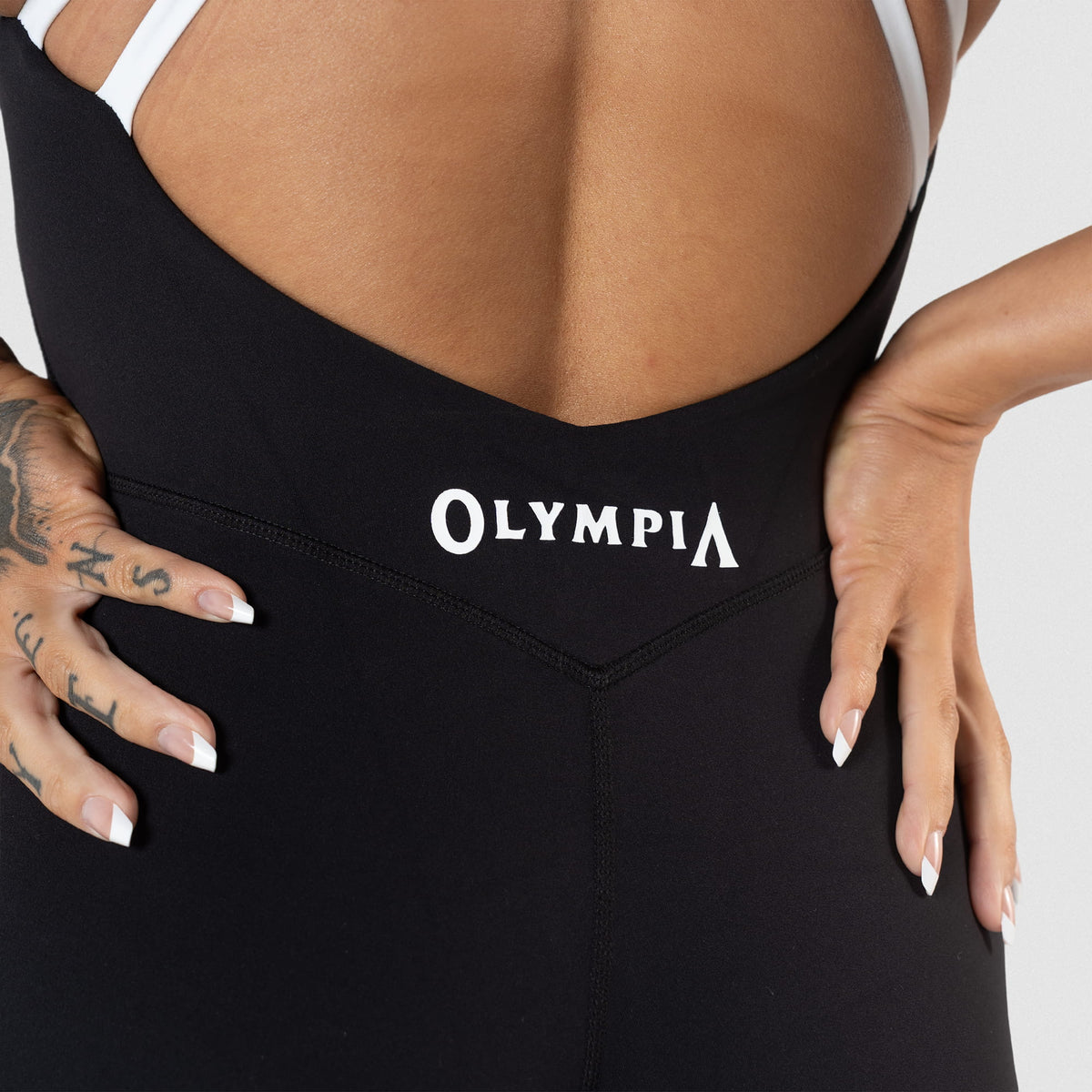 Glute seam of the Olympia Bodysuit in black that shows the white Olympia logo right above the stitchline