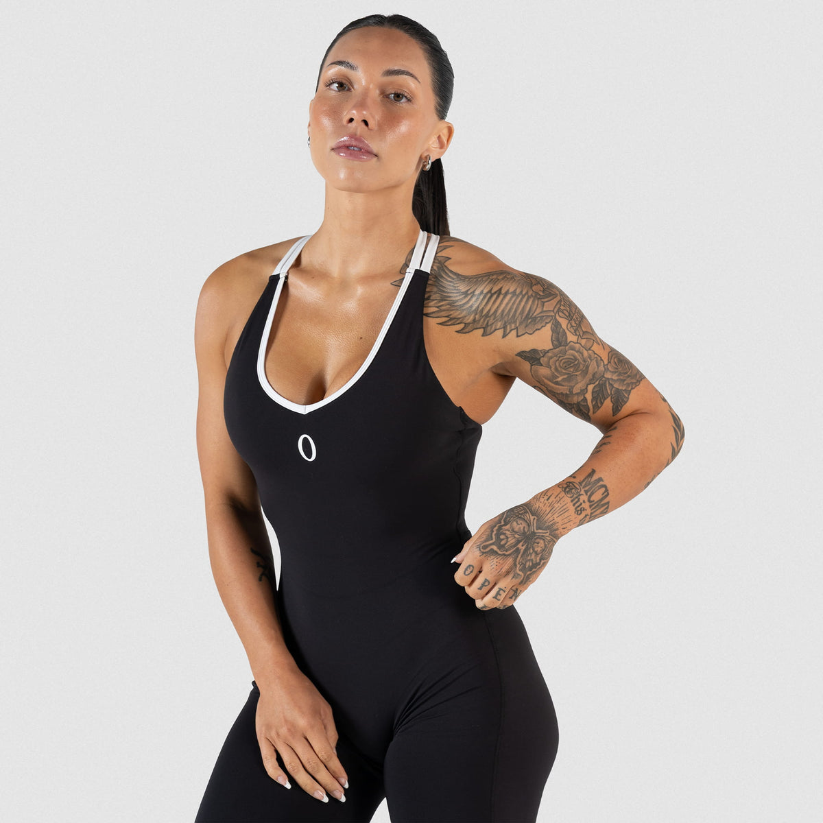 Torso of model wearing the Olympia Bodysuit displaying the black bodysuit with a V neckline that has white contrast details and an O logo on the chest