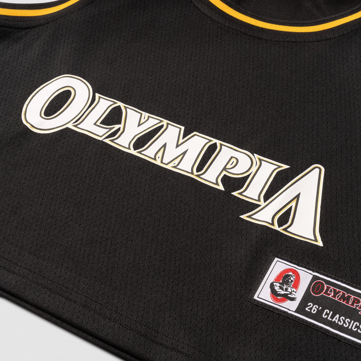Champions Gold Crop Jersey | Close up of white "Olympia" wordmark front logo