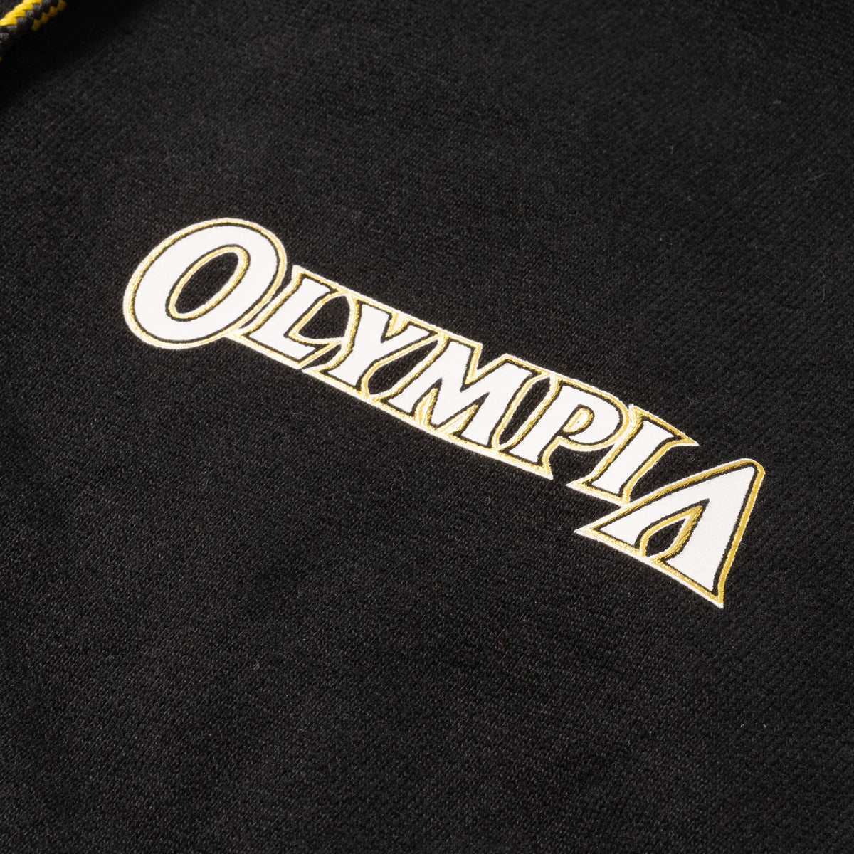 Champions Gold Cropped Zip-Up Hoodie | Front chest close up of gold and white "Olympia" wordmark logo