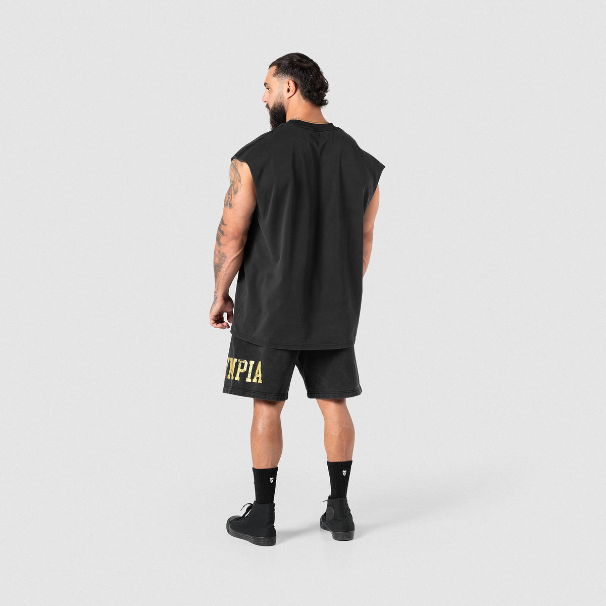 Full body back view of male model wearing the Joes Olympia Sweatshort paired with a black cut off tank