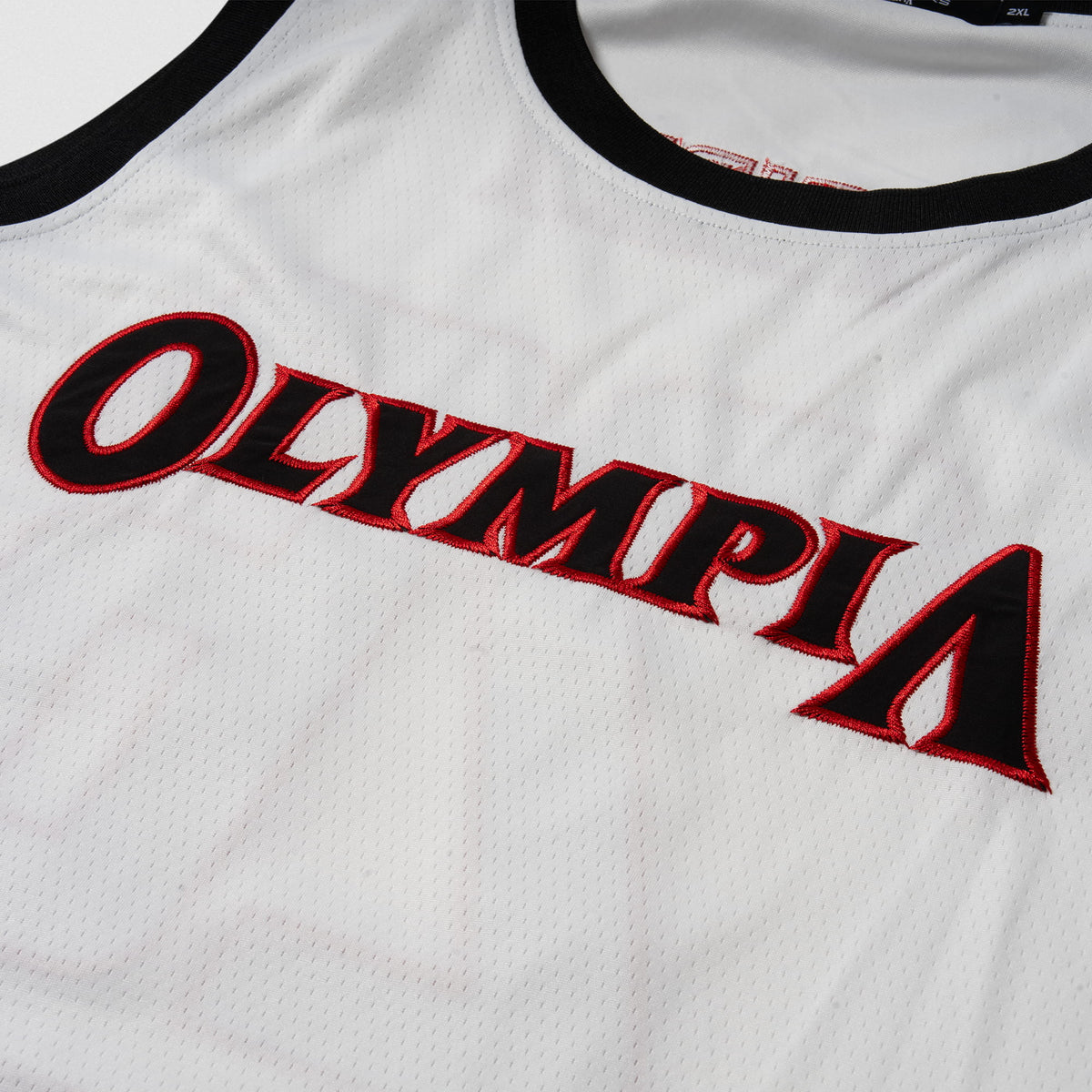 Signature Jersey | Close up of white mesh and black and red "Olympia" wordmark logo on the chest