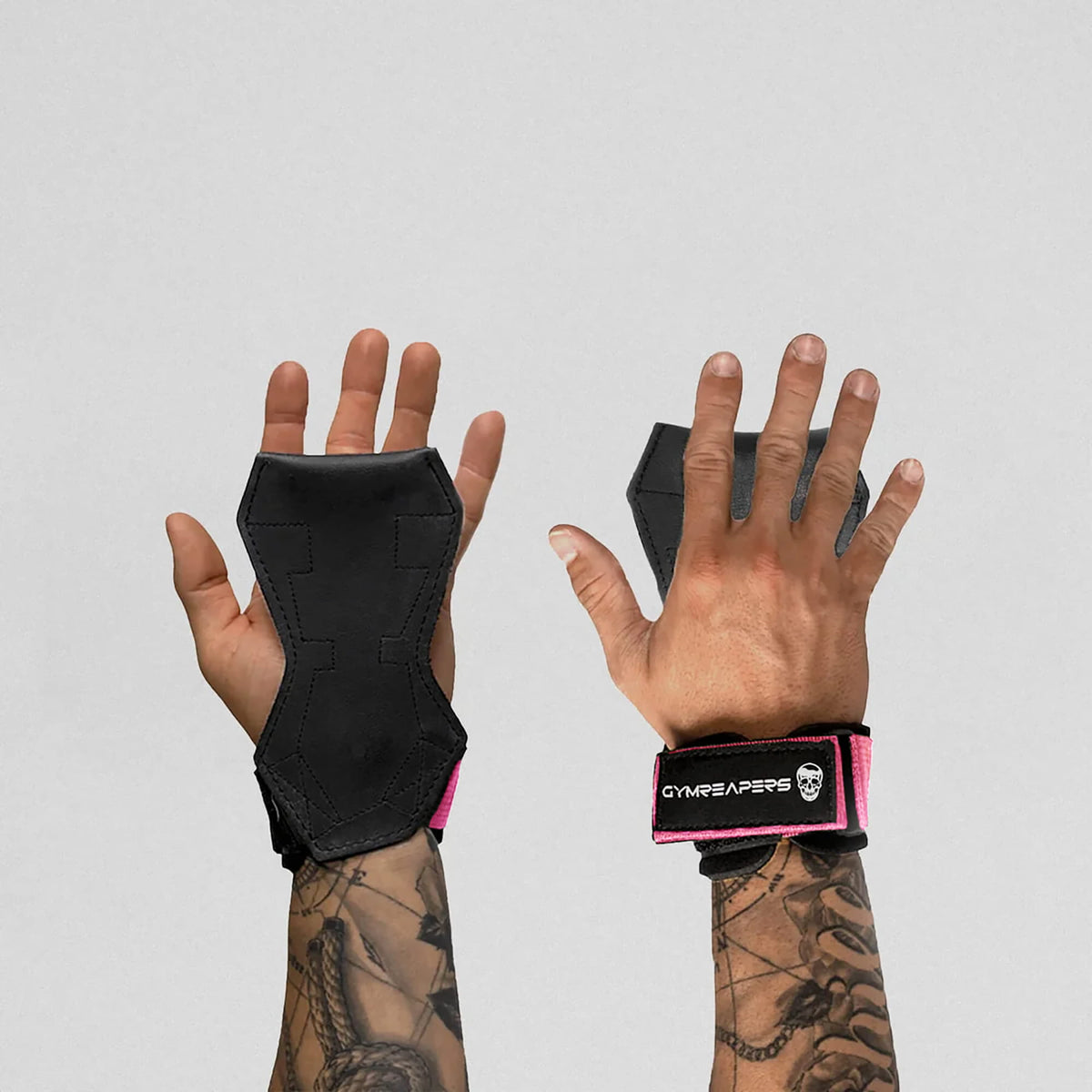 Gymreapers lifting grips pink on hands, one hand facing down and the other facing up to showcase both ends of the grips.