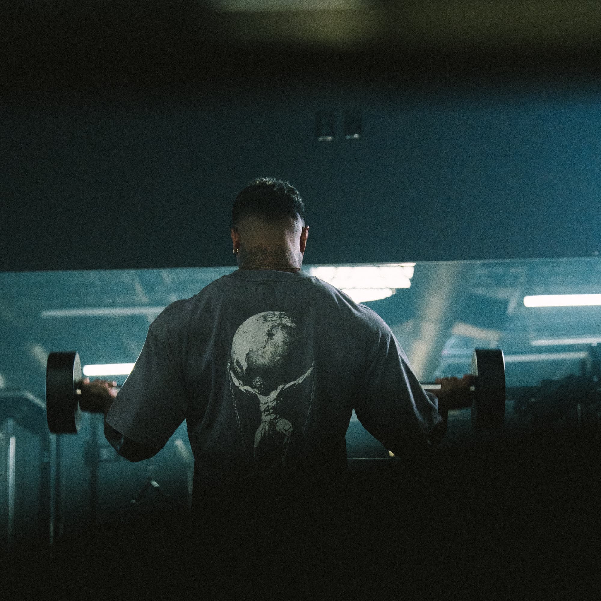 Athlete training in the As Above So Below Graphic Tee, highlighting the oversized fit and bold back graphic in a gym setting.