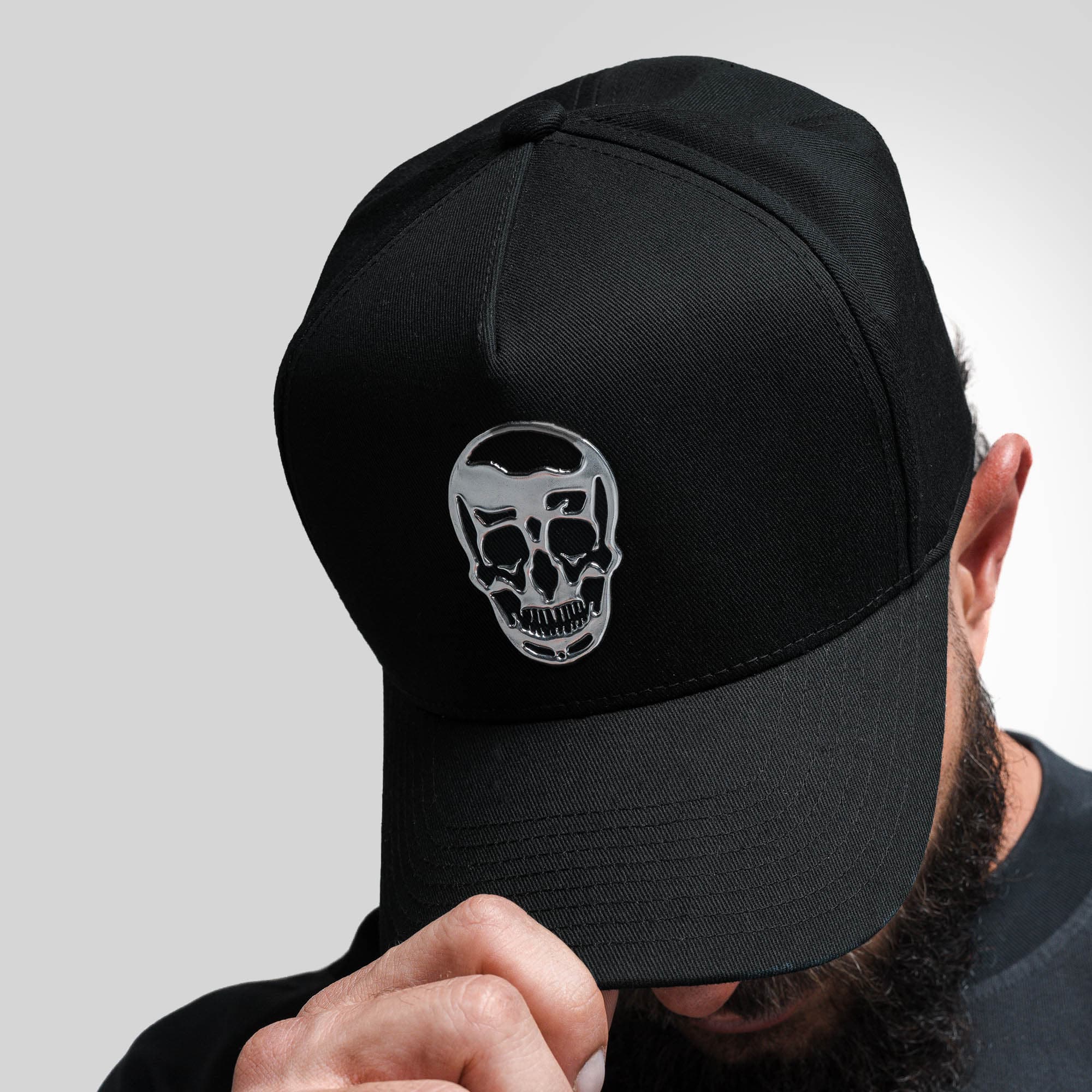 Athlete wearing 5-Panel Chrome Skull Hat looking down to showcase logo