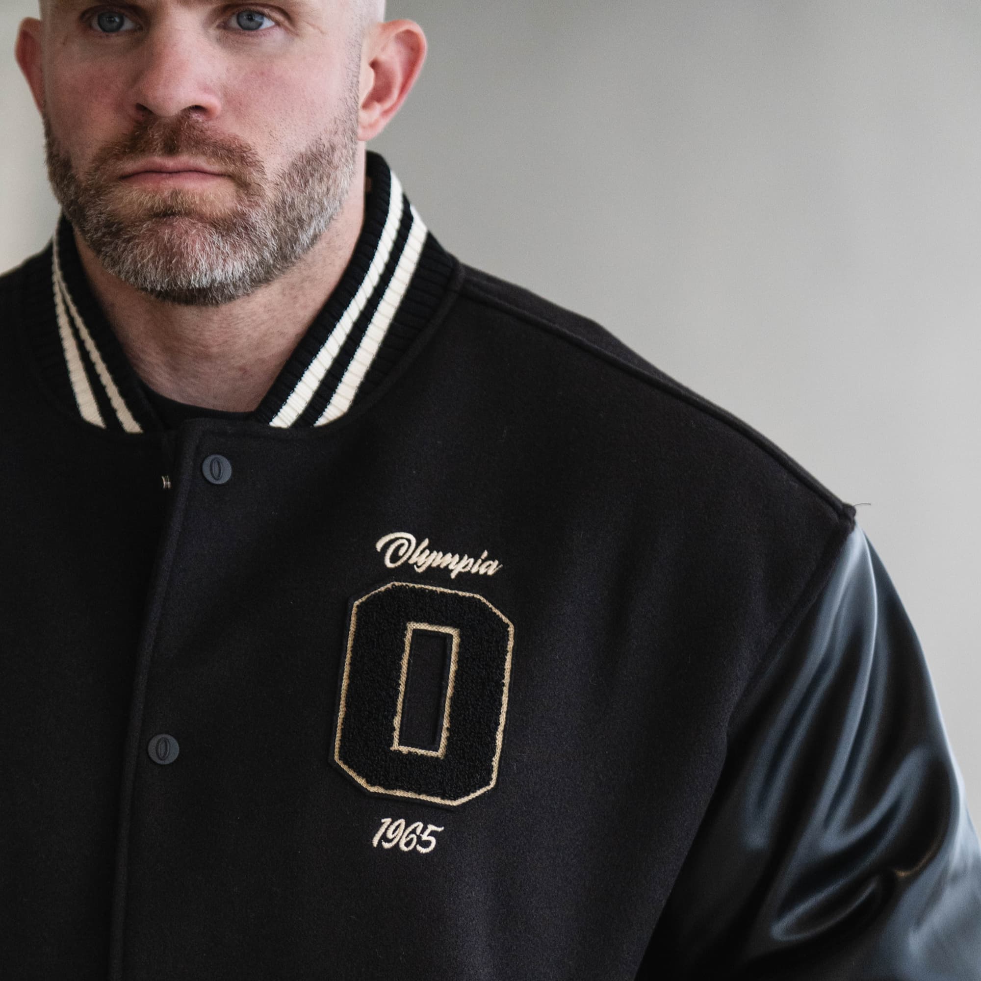 Olympia O Varsity Jacket on athlete close up shot of front graphic