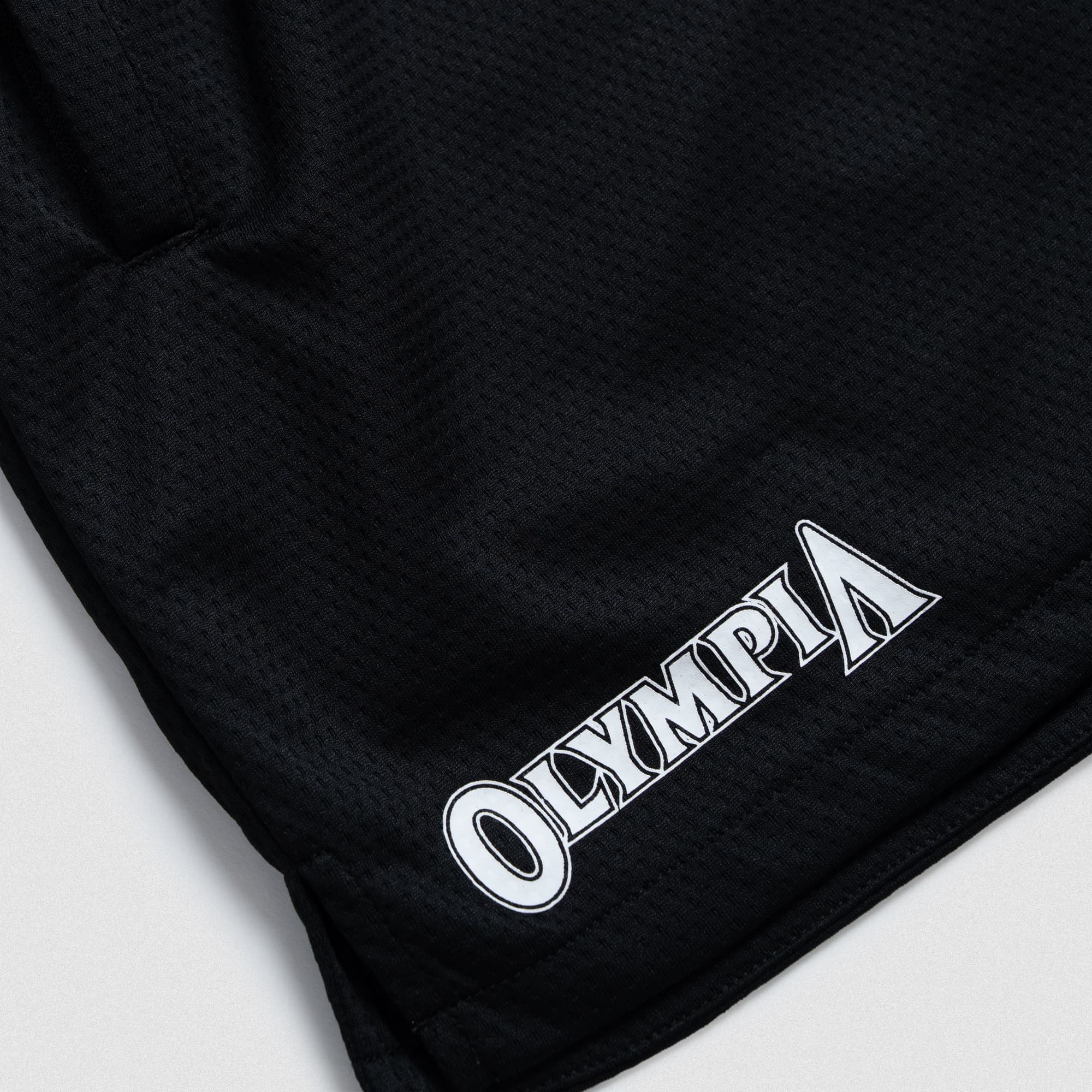 Bottom hem detail of Olympia O Mesh Shorts with white Olympia logo printed on the right leg