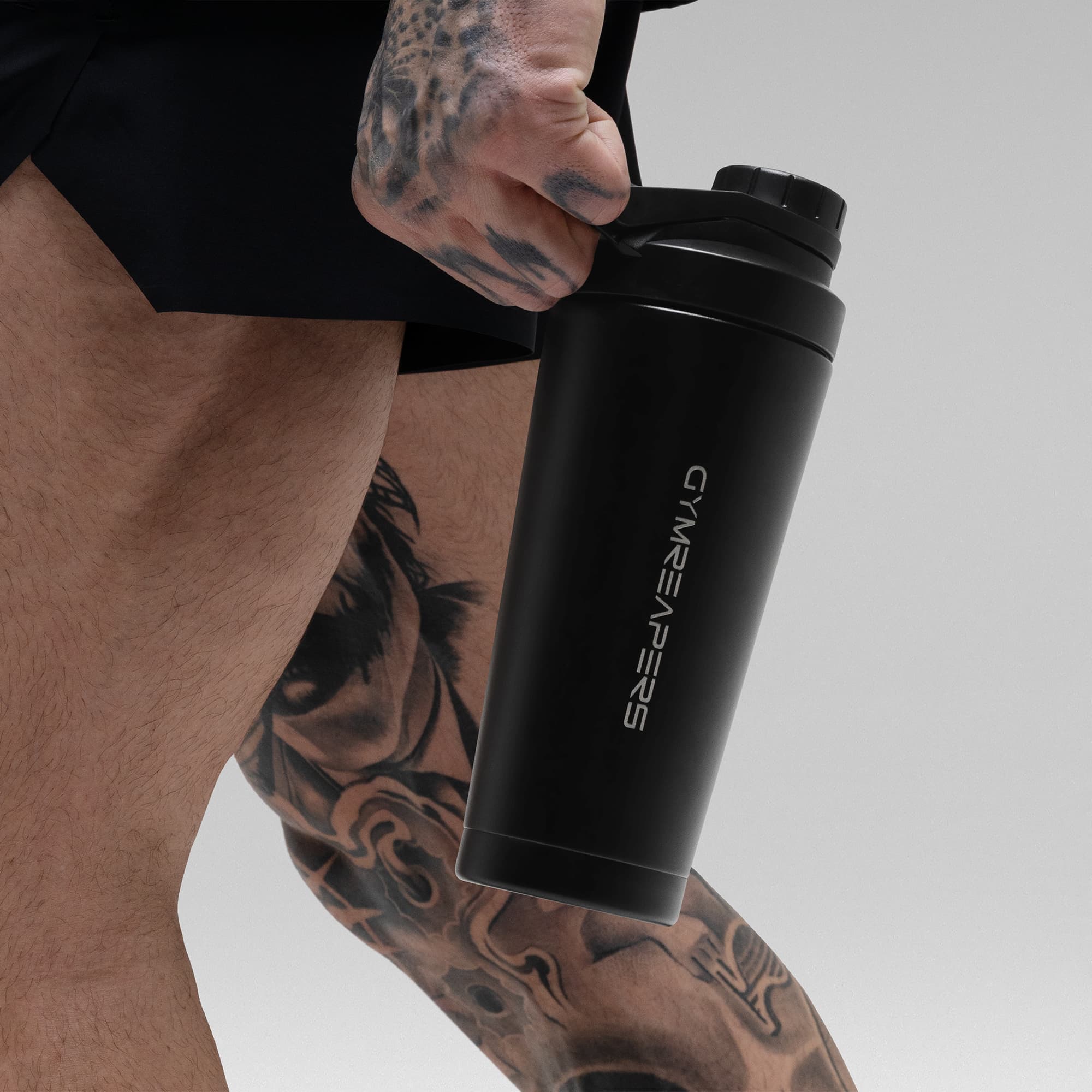 Athlete holding the Black Stainless Steel Shaker by the built in carry loop showcasing Gymreapers logo