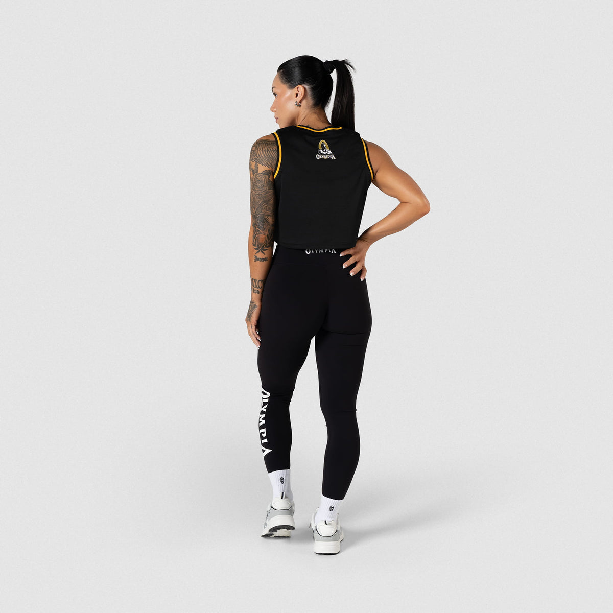 Champions Gold Crop Jersey | Back view of female model wearing the black jersey and matching black leggings