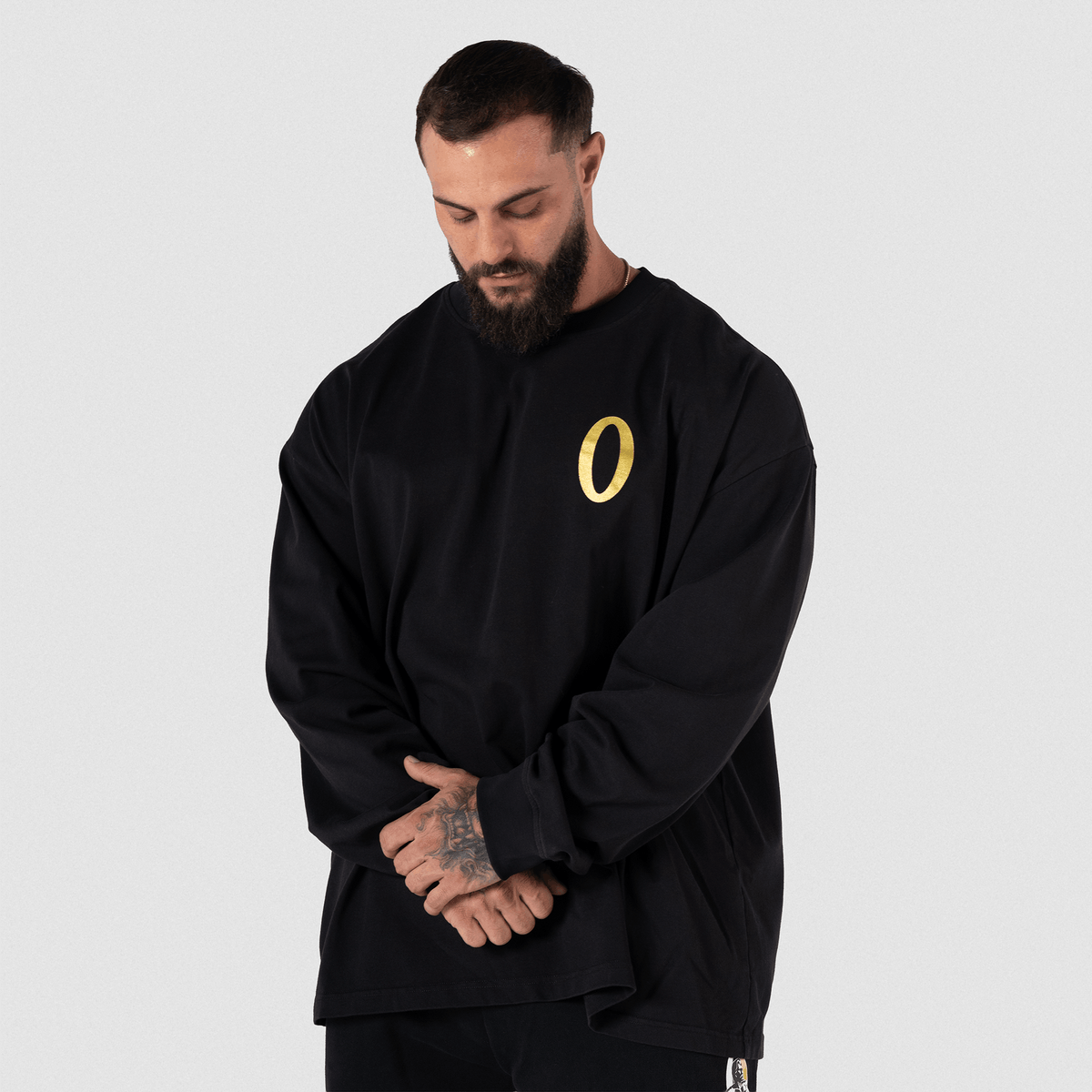 Man in black hoodie standing with arms crossed, front view