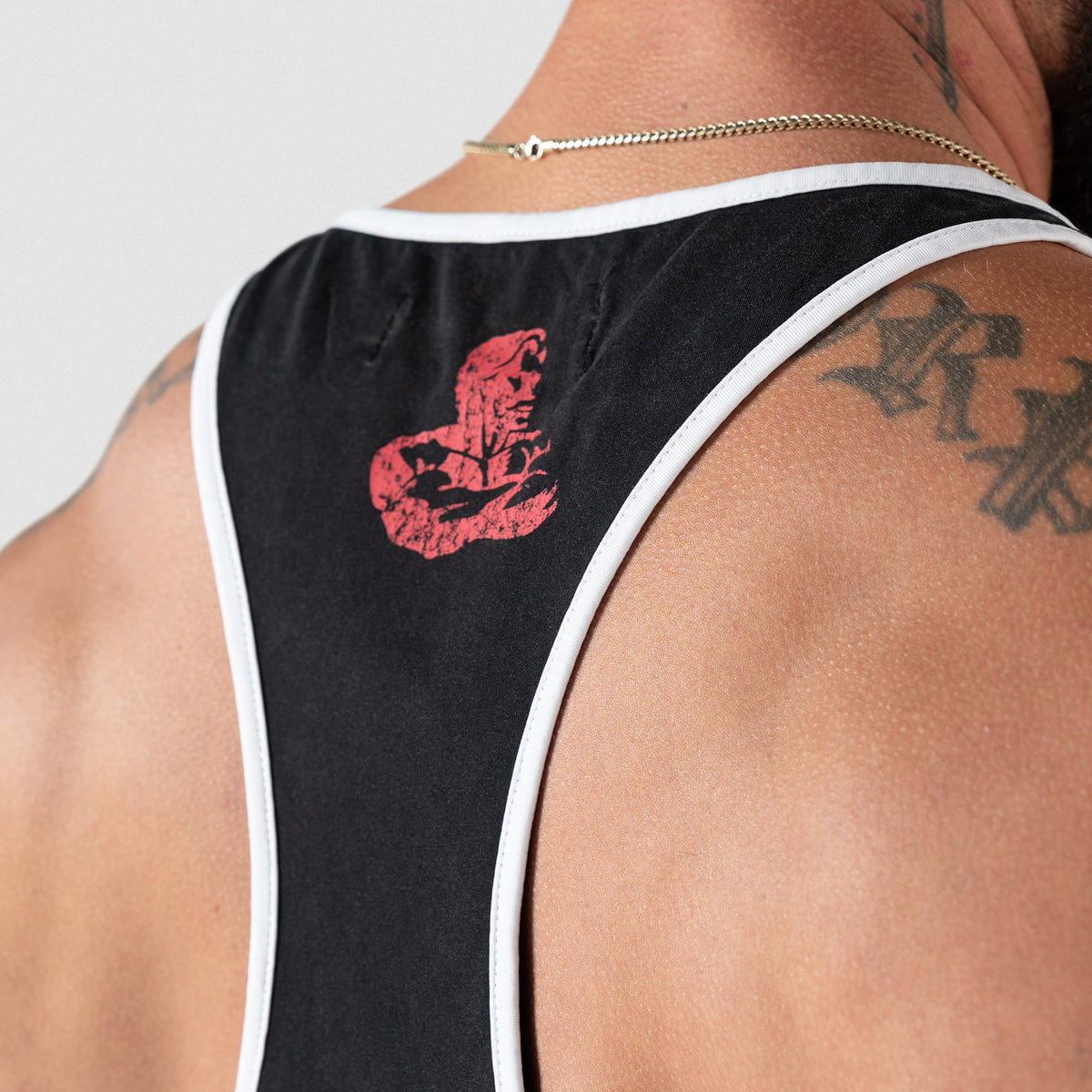 Close up view of distressed red Olympia logo found on the racerback of the Championship Stringer