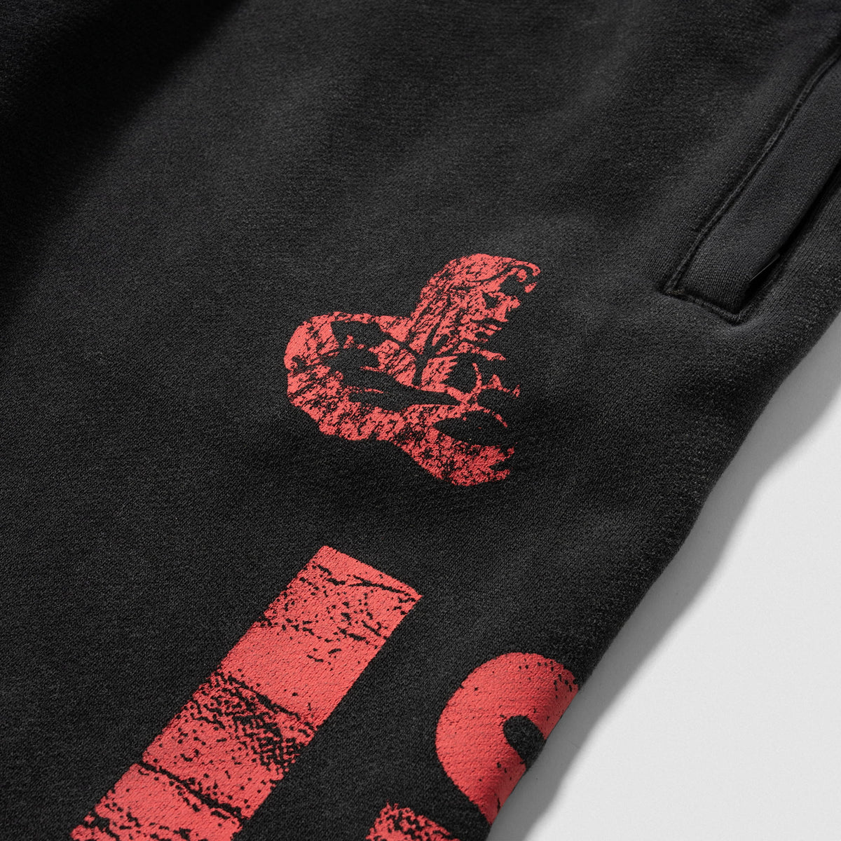 Close up of small red Olympia distressed logo directly below the pocket of the Championship Wide-Leg Jogger