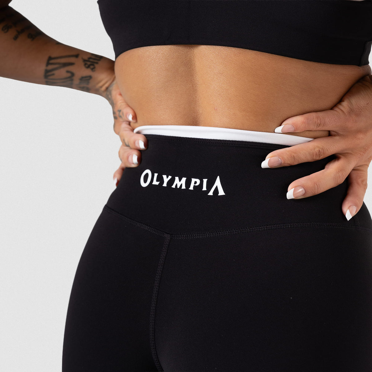 Back view of the Women's black Olympia Legging displaying the "Olympia" wordmark logo above the glute seam