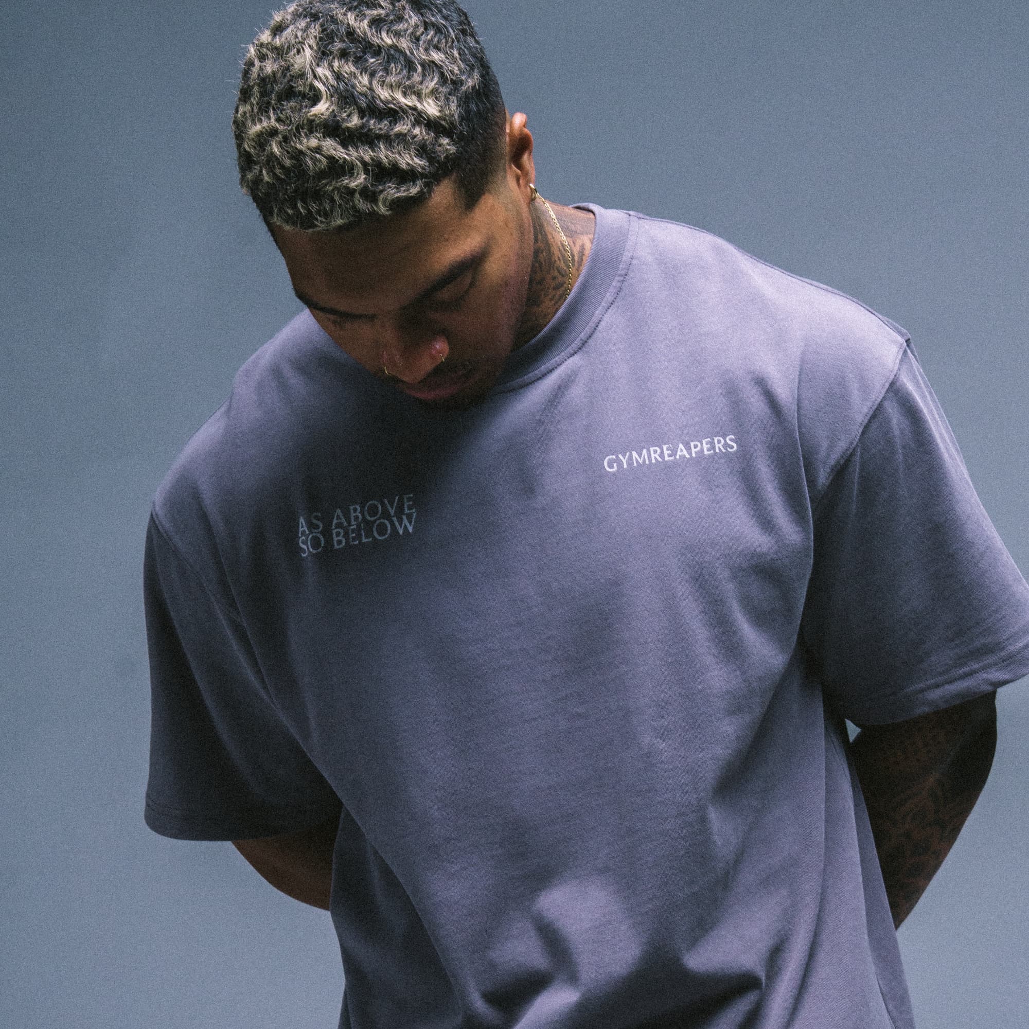 Athlete wearing the As Above So Below Graphic Tee in Amethyst Smoke, showing the front chest logos.