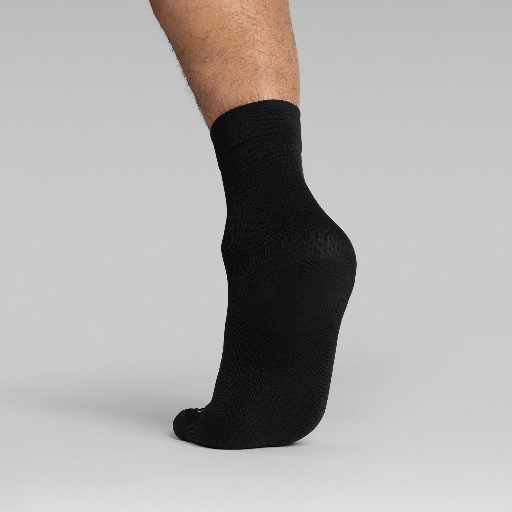 Athlete wearing the Black Stryda™ Crew Run Socks back view taking step