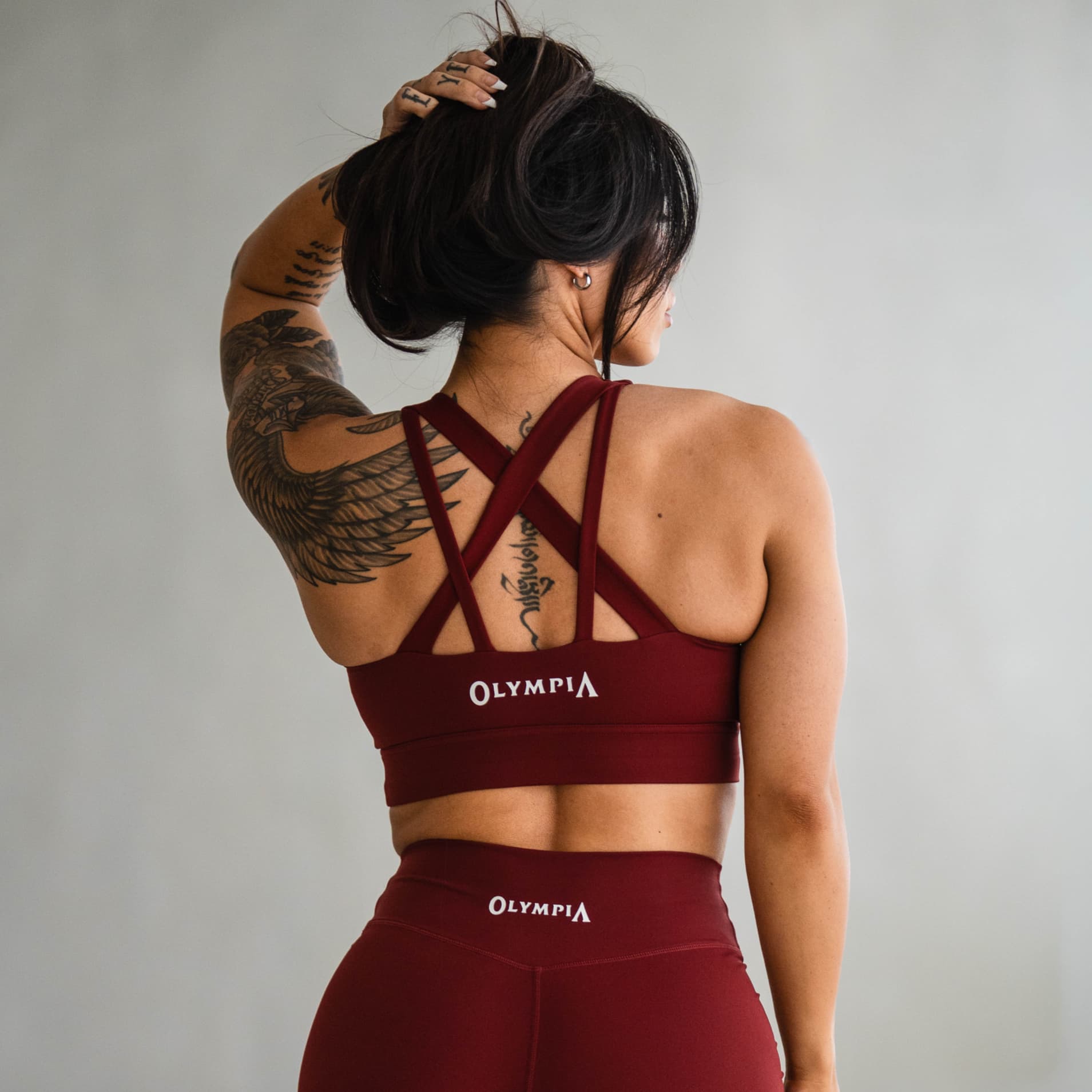 Model wearing the Olympia Harmony Bra, back view with cross-strap design and Olympia logo.