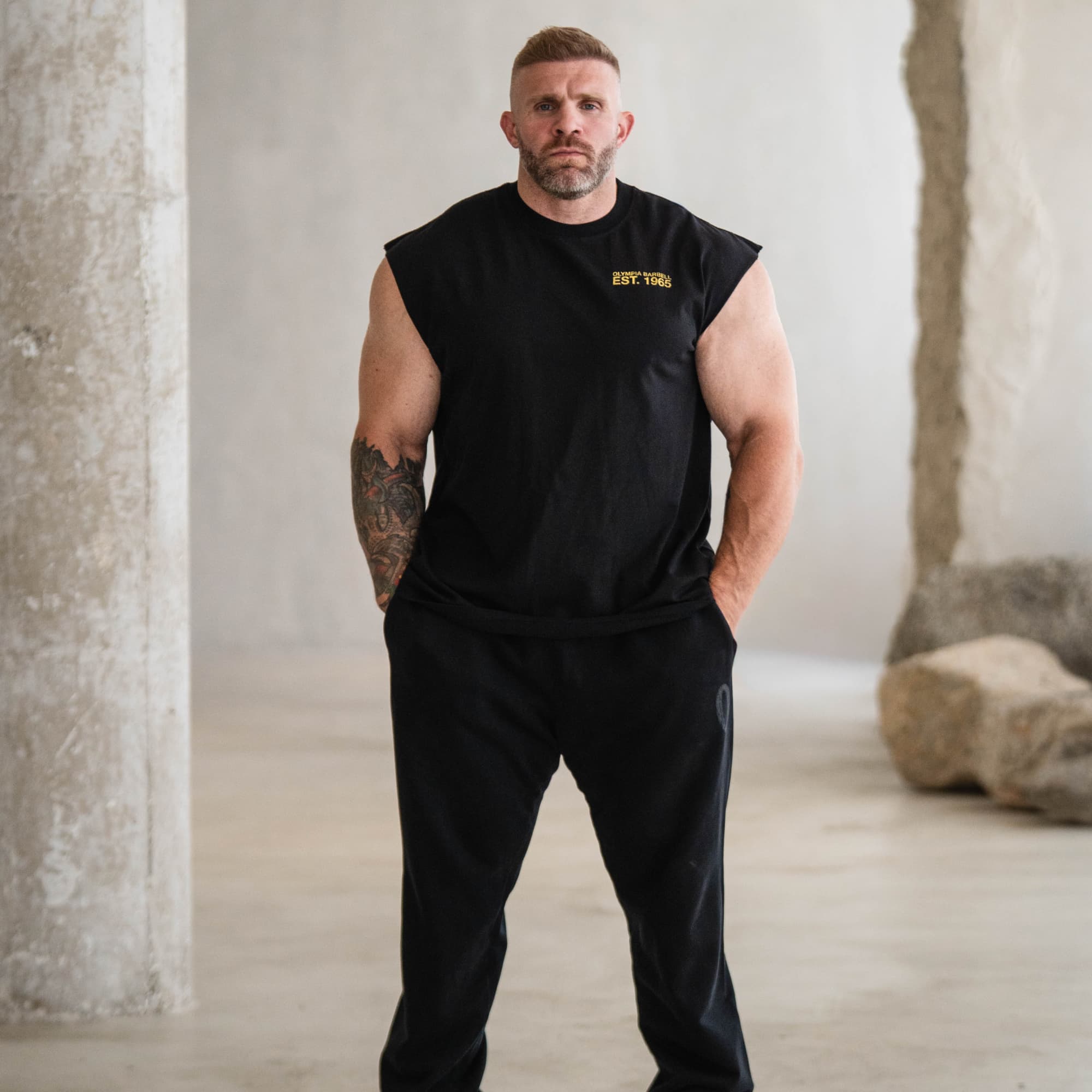 Model wearing the black Olympia Crest Cut Off shown from the front with chest graphic detail