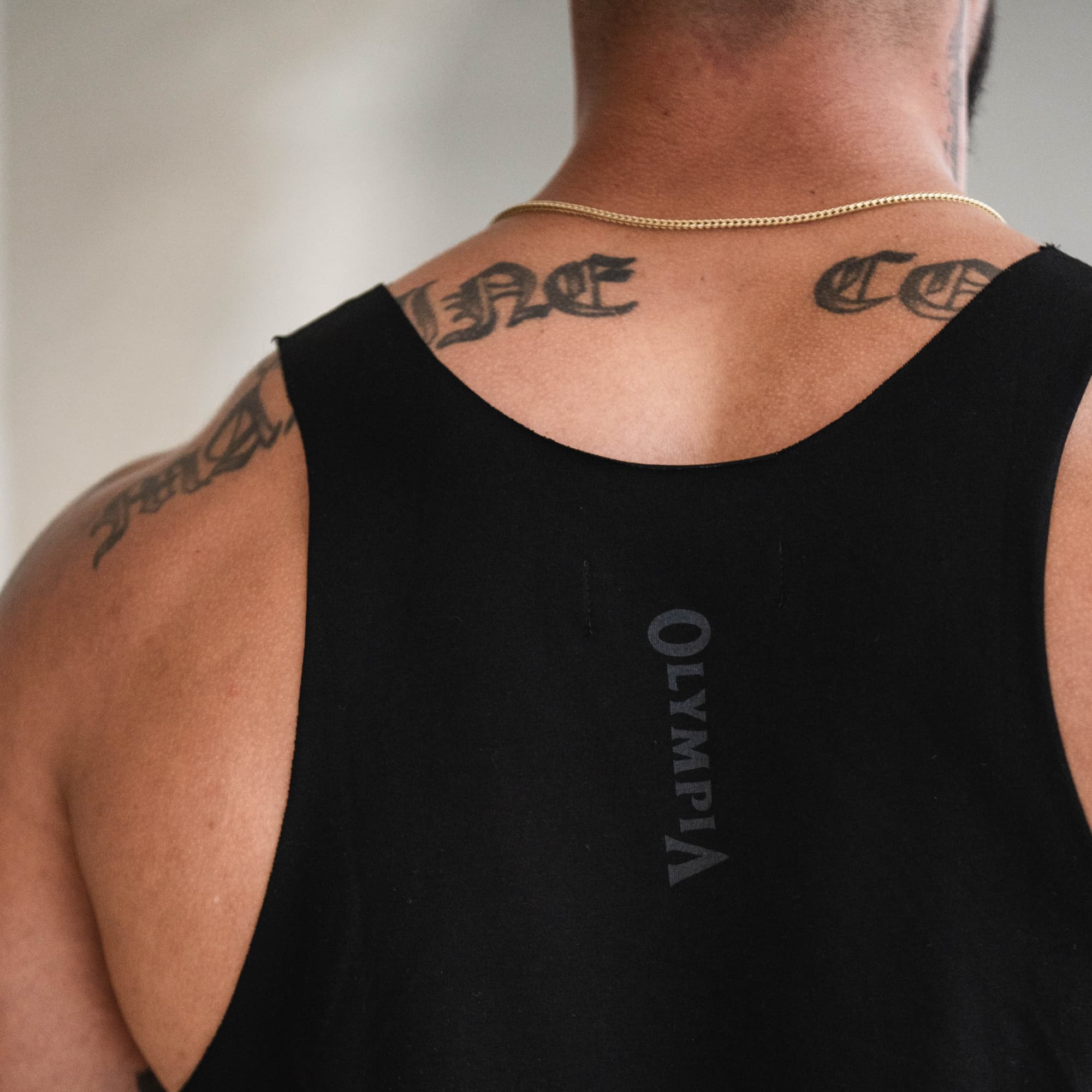 Close-up of back neckline on model showing vertical “Olympia” logo on Raw Hem Olympia Stringer.