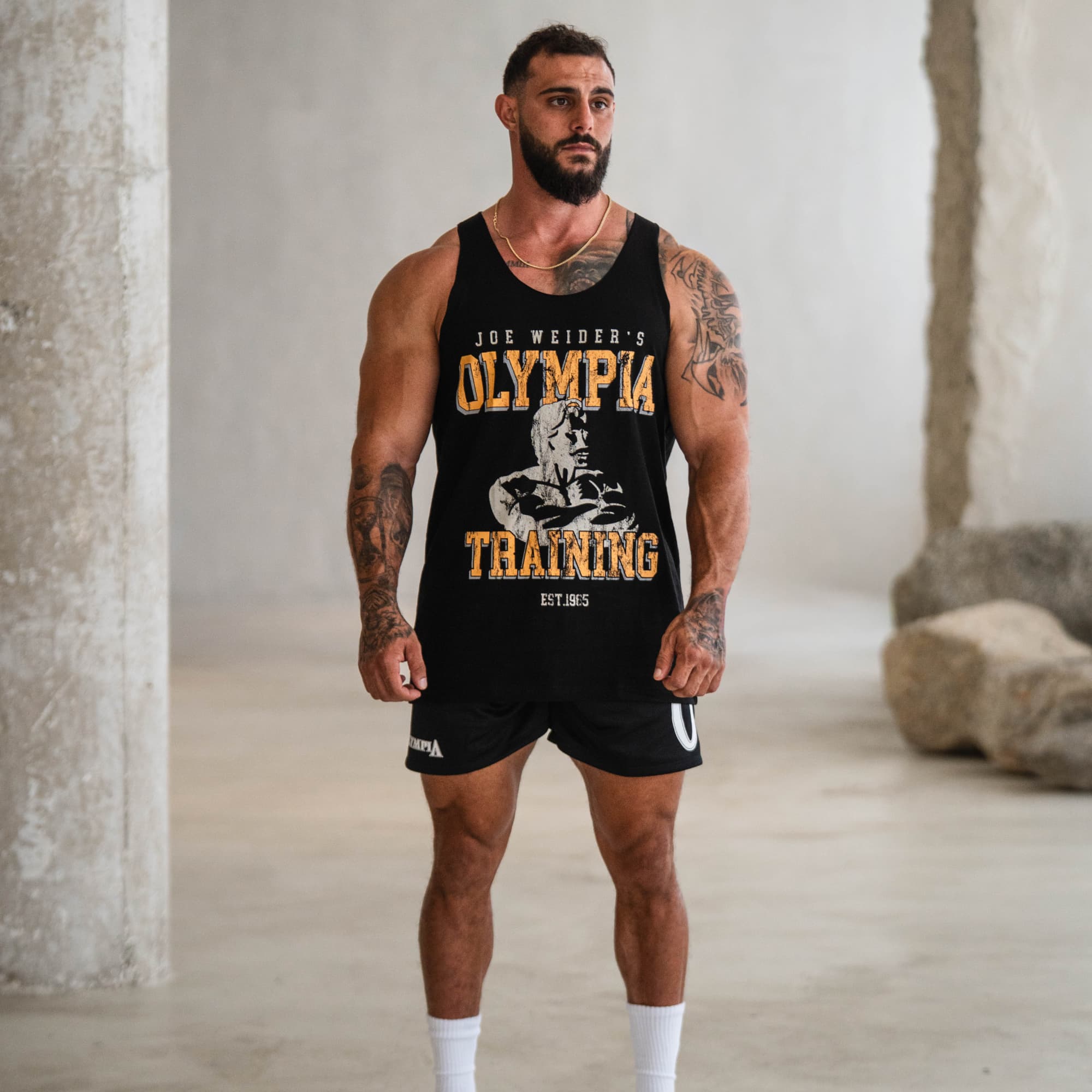 Model wearing the Raw Hem Olympia Training Stringer, full body view from the front showcasing the graphic design.