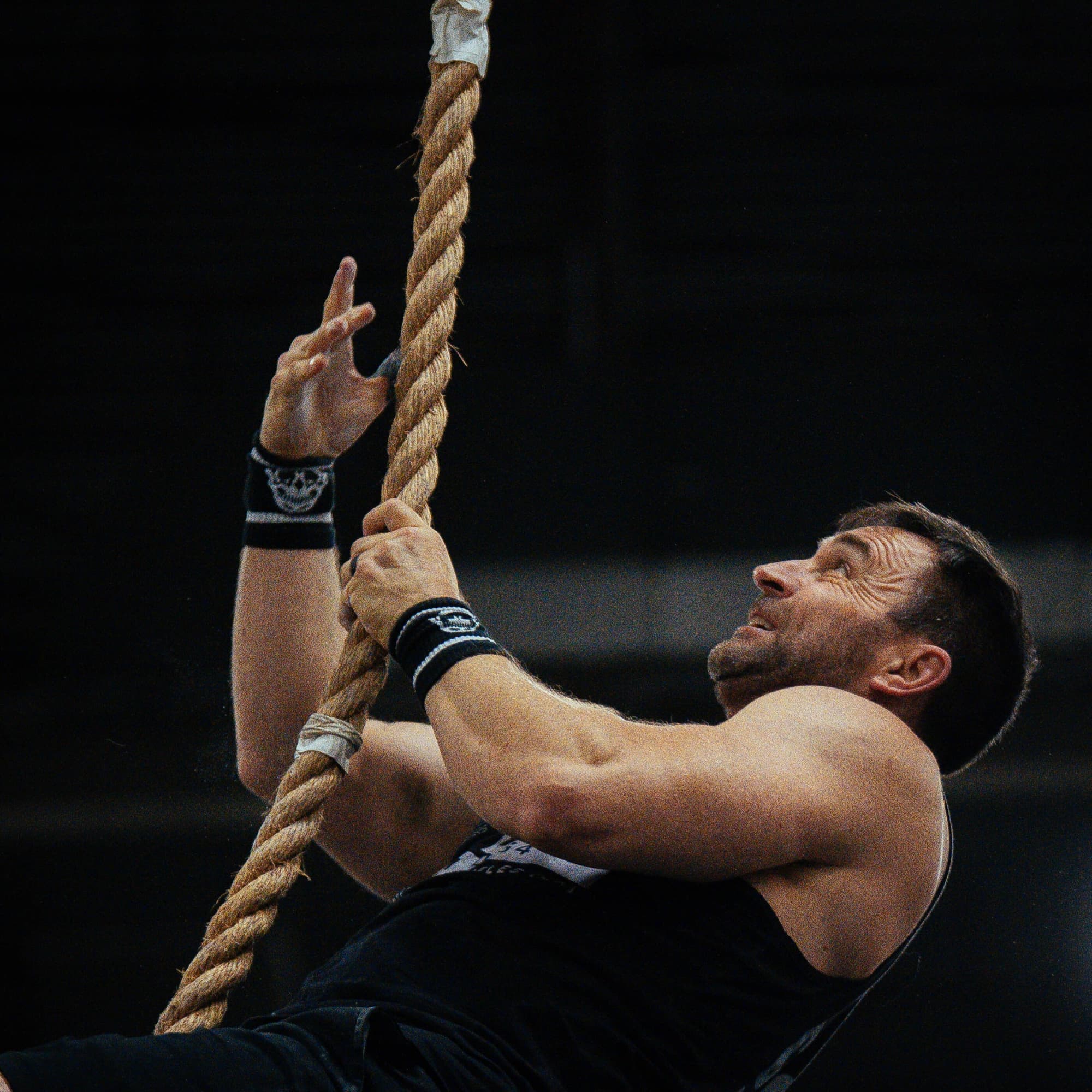 athlete climbing rope with skull wrist bands on
