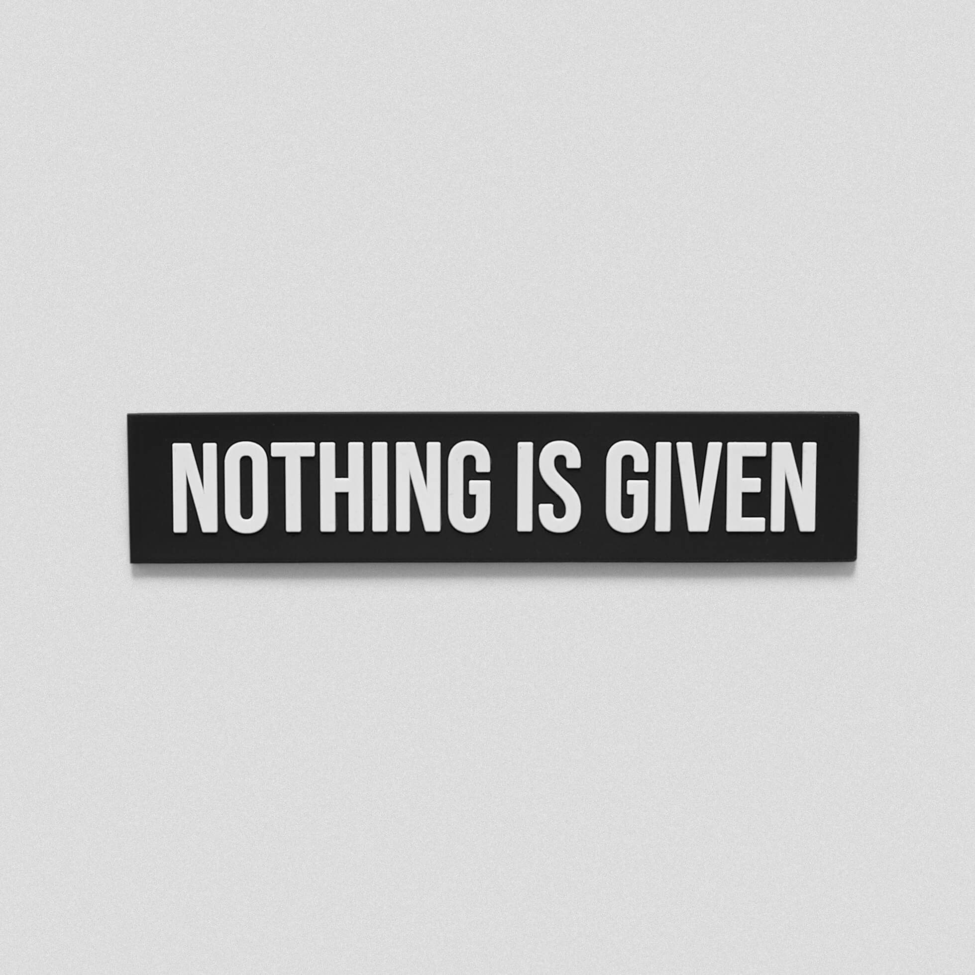 A black white patch that says Nothing Is Given across the middle
