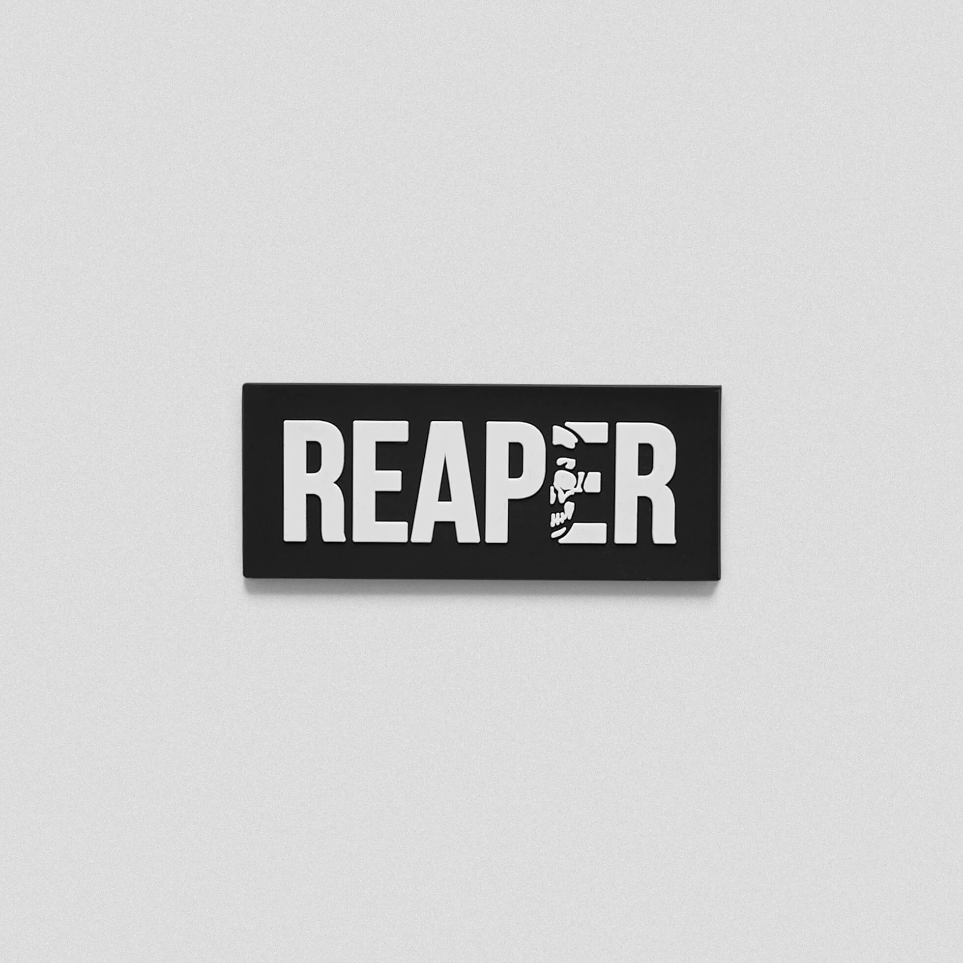 A black and white patch that says Reaper across the middle. In the letter E, there is a skull outline.